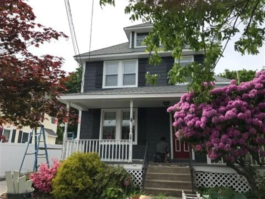a house with a porch with a ladder and a tree